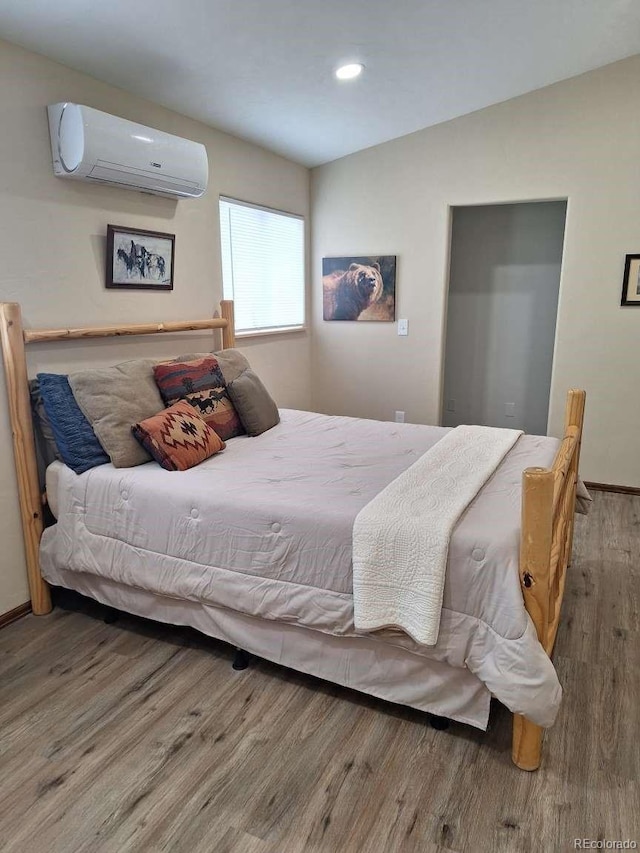 bedroom with an AC wall unit and wood-type flooring