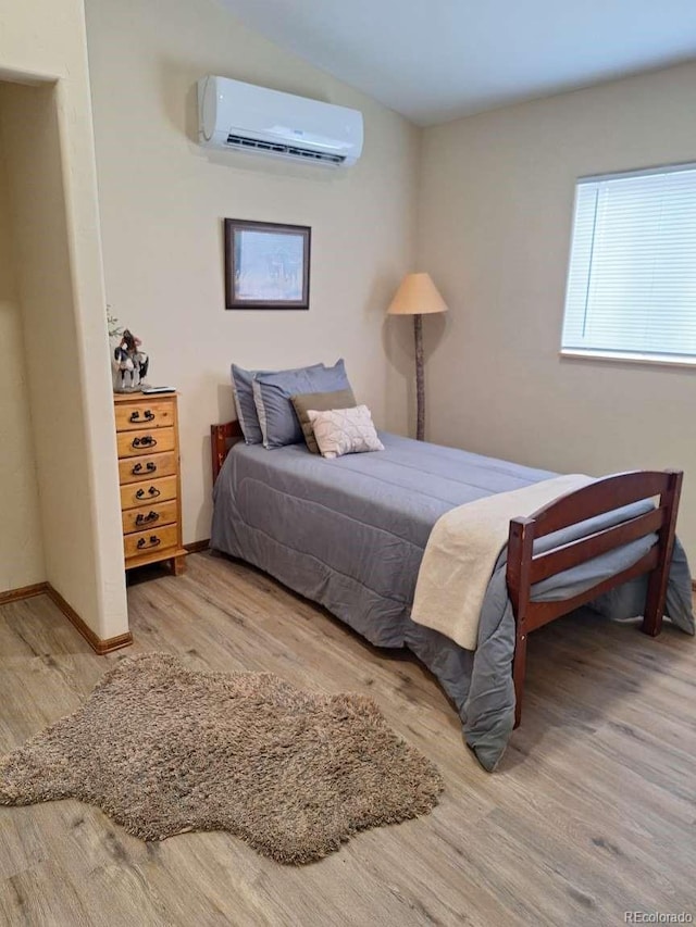 bedroom with a wall mounted AC and hardwood / wood-style flooring