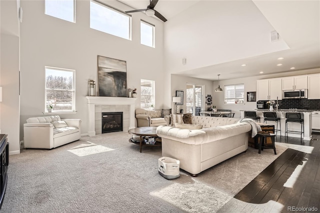 living room with a tile fireplace, visible vents, plenty of natural light, and ceiling fan