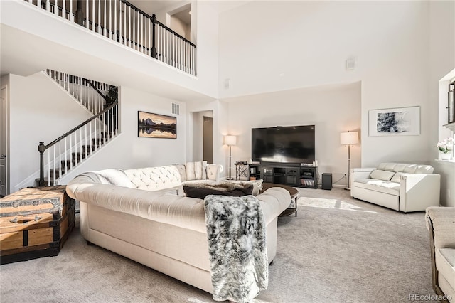 carpeted living room featuring visible vents, a high ceiling, and stairs