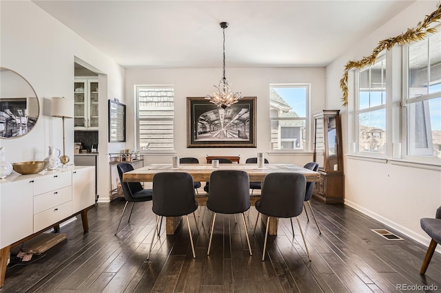 dining room featuring an inviting chandelier, baseboards, visible vents, and dark wood-type flooring