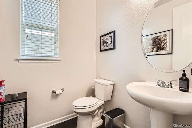 bathroom featuring toilet, a sink, and baseboards