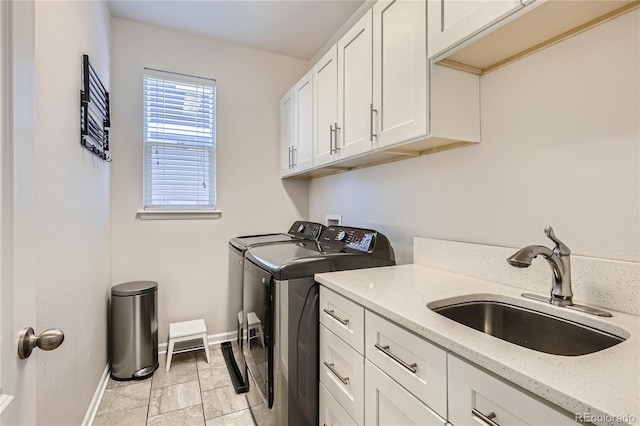 clothes washing area with independent washer and dryer, a sink, cabinet space, and baseboards