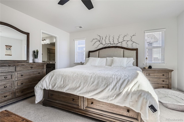 bedroom with light carpet, a ceiling fan, visible vents, and ensuite bathroom