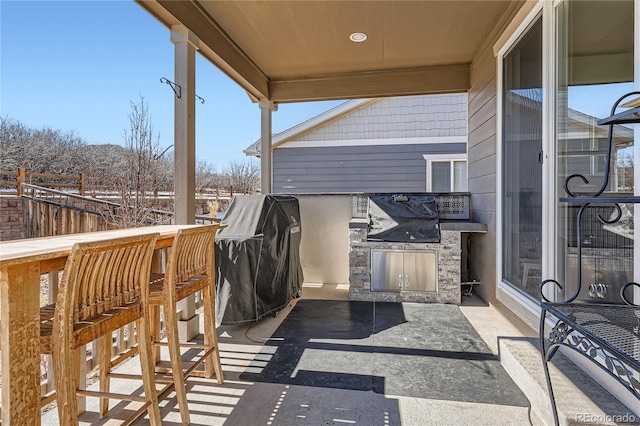 snow covered patio with fence, a bar, and area for grilling