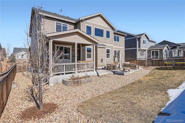 view of front of house featuring a trampoline, a fenced backyard, a residential view, and a patio