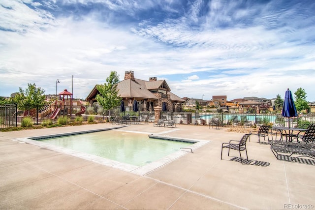 pool featuring a patio area, playground community, and fence