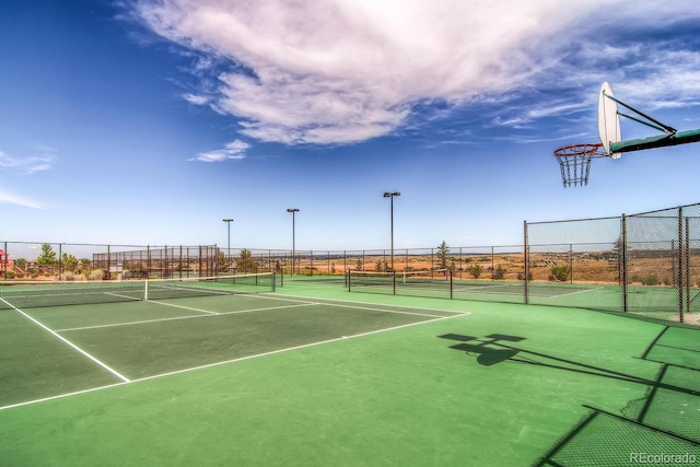 view of tennis court featuring community basketball court and fence