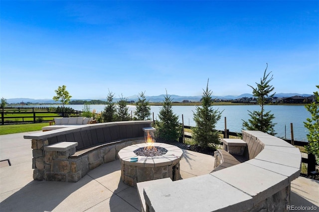 view of patio with a water and mountain view and an outdoor fire pit