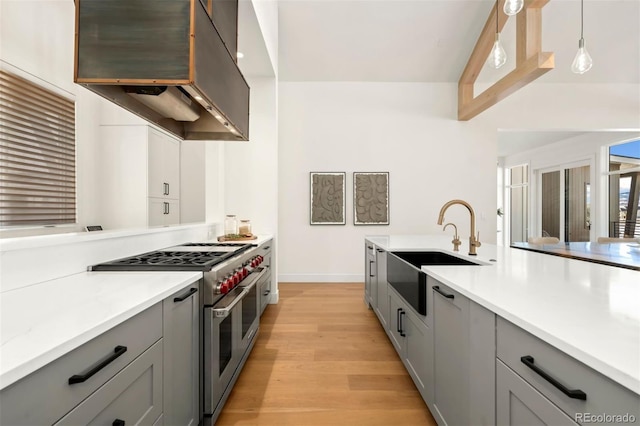 kitchen with sink, gray cabinets, double oven range, hanging light fixtures, and exhaust hood