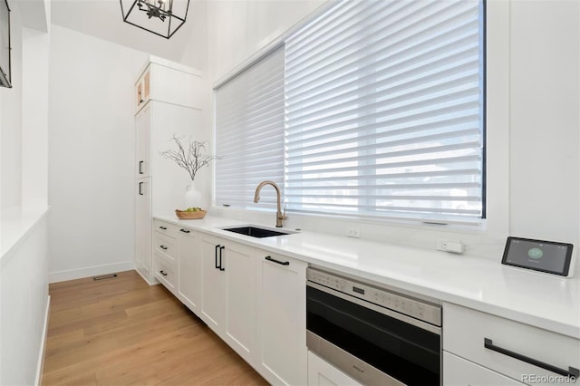 kitchen with light hardwood / wood-style floors, sink, and white cabinets