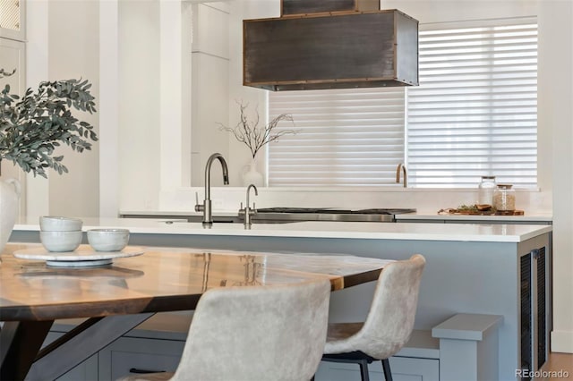 kitchen with ventilation hood, sink, and a breakfast bar area