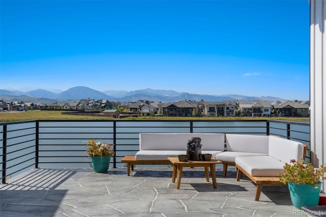 view of patio featuring a balcony, outdoor lounge area, and a water and mountain view