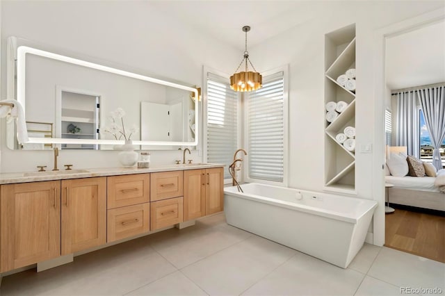 bathroom featuring a notable chandelier, vanity, tile patterned flooring, and a wealth of natural light