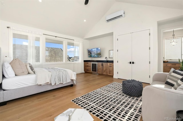 bedroom featuring light hardwood / wood-style flooring, high vaulted ceiling, a closet, and a wall mounted AC