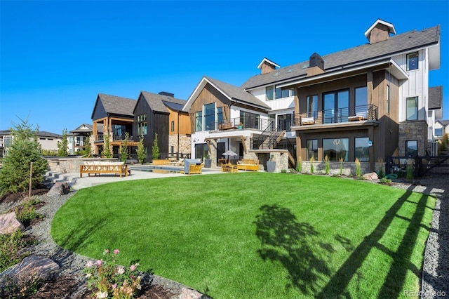 rear view of property with a pool, a yard, a patio, and a balcony