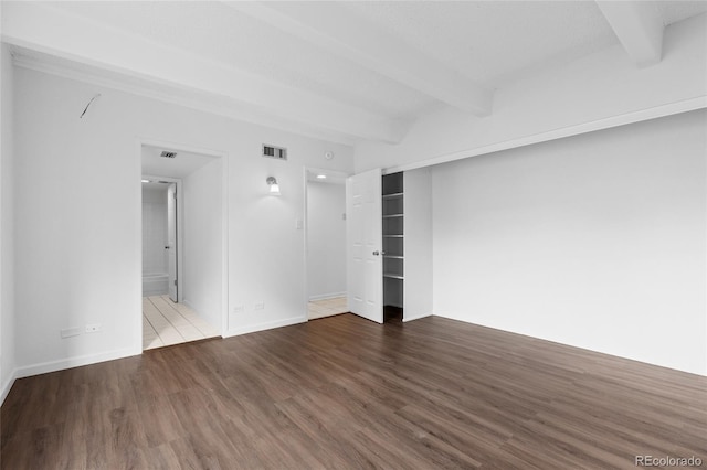 spare room featuring beamed ceiling and hardwood / wood-style floors