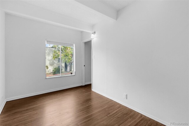 unfurnished room featuring a textured ceiling and dark hardwood / wood-style flooring