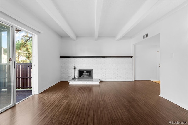 unfurnished living room featuring hardwood / wood-style floors, beamed ceiling, and a brick fireplace