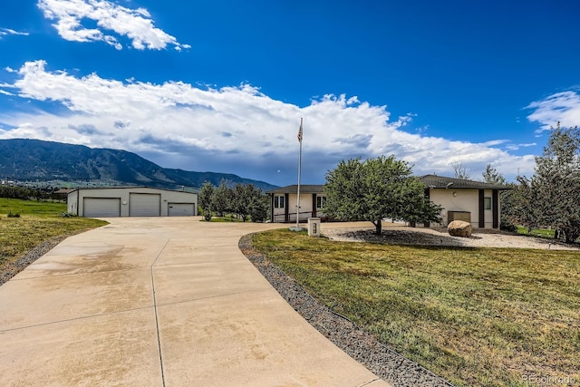 16710 Vincent Ave, Monument, CO 80132 - view of front facade with a mountain view, an outbuilding, a detached garage, stucco siding, and a front lawn
