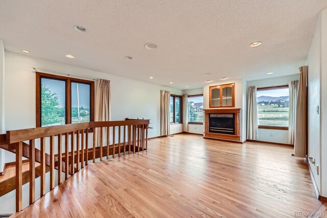 16710 Vincent Ave, Monument, CO 80132 - living area with healthy amount of natural light, light wood finished floors, a glass covered fireplace, recessed lighting, and a textured ceiling
