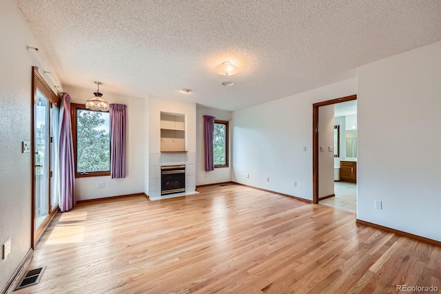 16710 Vincent Ave, Monument, CO 80132 - unfurnished living room featuring a textured ceiling, light wood-type flooring, and a tile fireplace