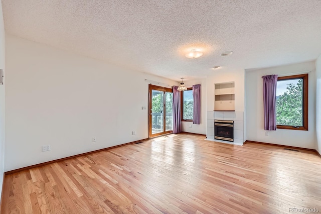 16710 Vincent Ave, Monument, CO 80132 - unfurnished living room with a textured ceiling, light wood finished floors, and a tile fireplace
