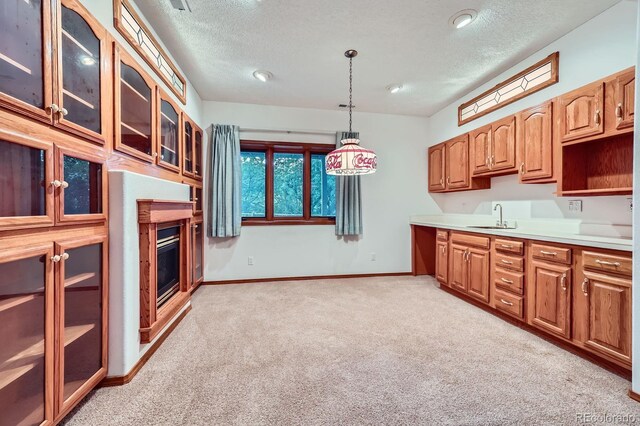 16710 Vincent Ave, Monument, CO 80132 - kitchen featuring light carpet, glass insert cabinets, a textured ceiling, a glass covered fireplace, and hanging light fixtures