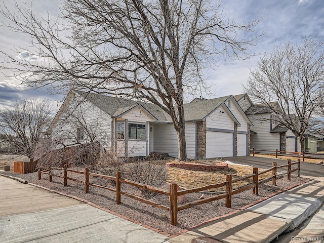 view of front facade with an attached garage, a fenced front yard, a shingled roof, and concrete driveway