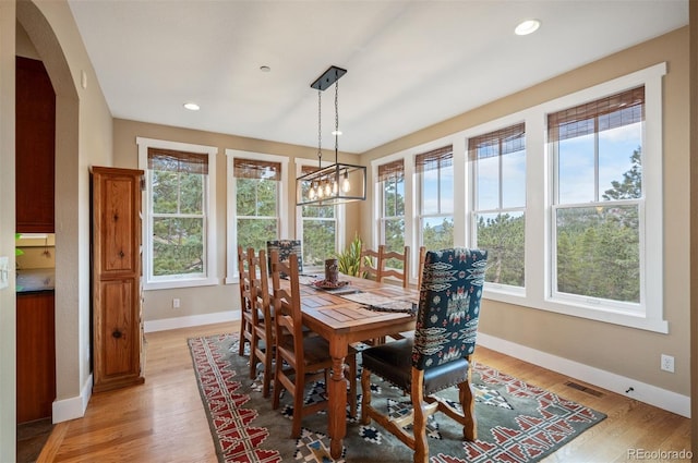 1055 Divide View Dr, Golden, CO 80403 - dining area featuring visible vents, arched walkways, light wood-type flooring, baseboards, and a notable chandelier