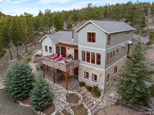 1055 Divide View Dr, Golden, CO 80403 - back of house with a shingled roof, a view of trees, a wooden deck, and stone siding