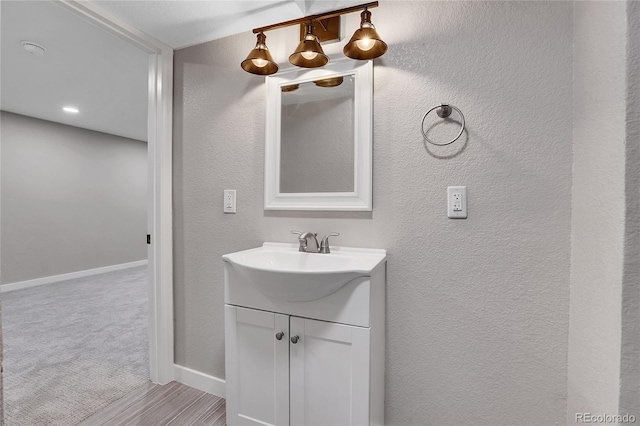 bathroom with vanity, baseboards, and a textured wall