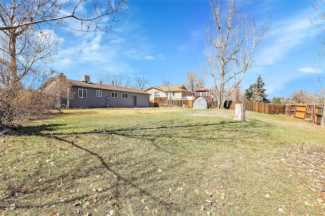 view of yard featuring a storage shed, an outbuilding, and a fenced backyard