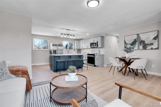 living area with visible vents, baseboards, and light wood finished floors