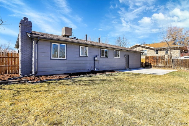 back of house with a yard, a chimney, a patio, and fence