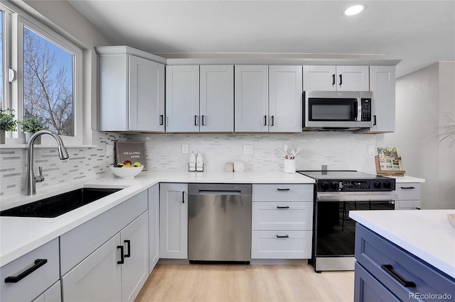 kitchen featuring a sink, stainless steel appliances, light wood-style flooring, and light countertops