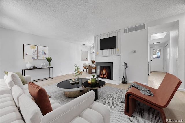 living room with a textured ceiling, visible vents, and wood finished floors