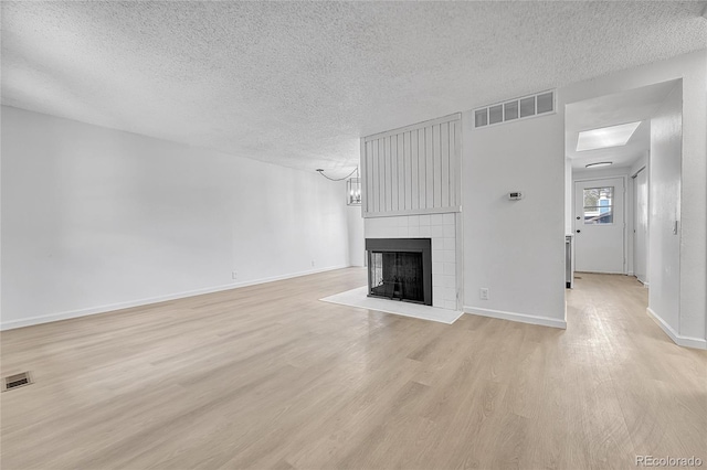 unfurnished living room featuring a textured ceiling, visible vents, and light wood finished floors