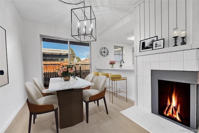 dining room featuring baseboards, light wood finished floors, and a tile fireplace