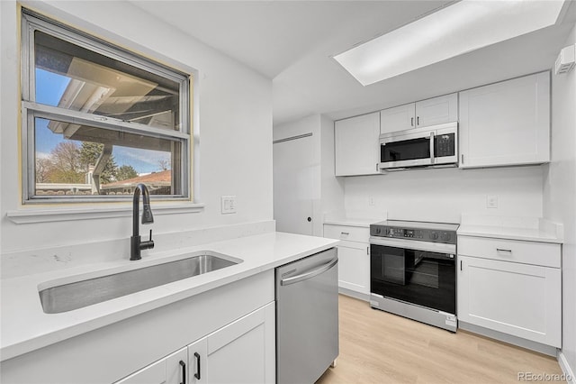 kitchen with a sink, dishwasher, light countertops, range with electric cooktop, and white cabinetry