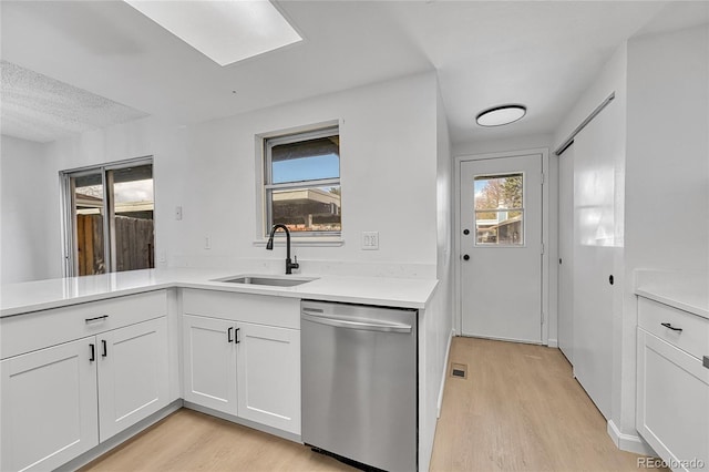 kitchen with a sink, light wood-style flooring, dishwasher, and white cabinetry