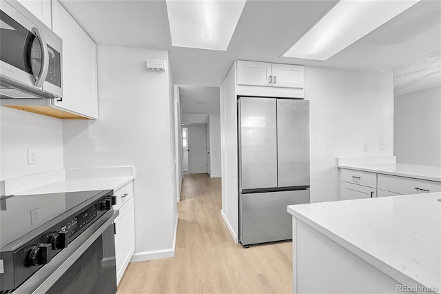 kitchen featuring light wood-type flooring, white cabinetry, baseboards, and stainless steel appliances