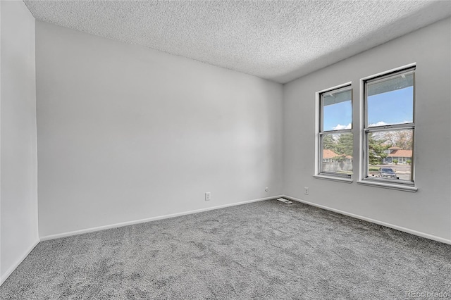 spare room with baseboards, carpet, a textured ceiling, and visible vents