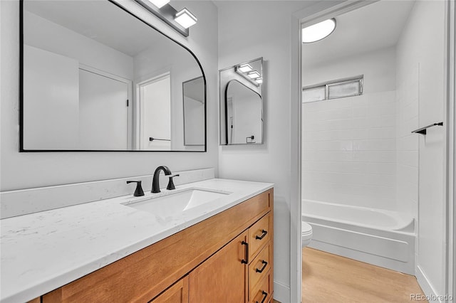bathroom featuring toilet, washtub / shower combination, wood finished floors, and vanity