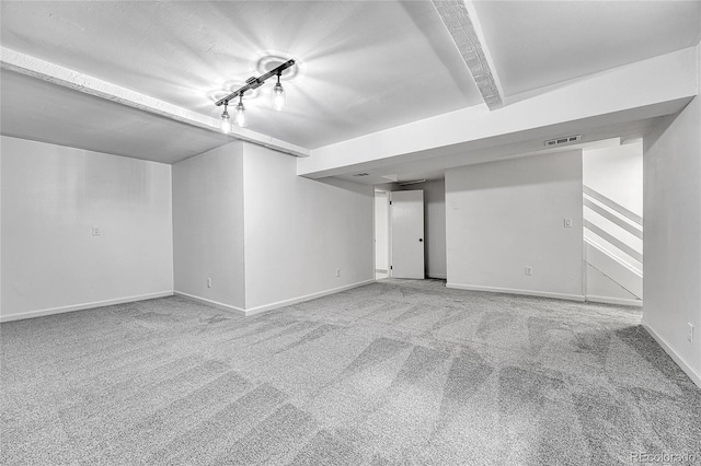finished below grade area with baseboards, carpet, rail lighting, and visible vents