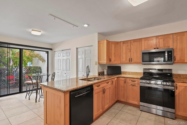 kitchen featuring light stone countertops, kitchen peninsula, sink, and appliances with stainless steel finishes