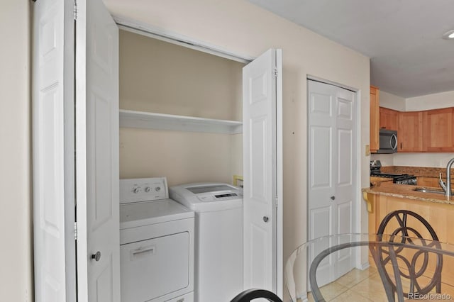 laundry room featuring sink, light tile patterned floors, and independent washer and dryer