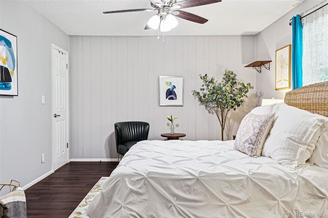 bedroom featuring a textured ceiling, dark hardwood / wood-style floors, wooden walls, and ceiling fan