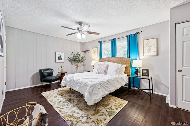 bedroom featuring wood walls, dark hardwood / wood-style floors, a textured ceiling, and ceiling fan