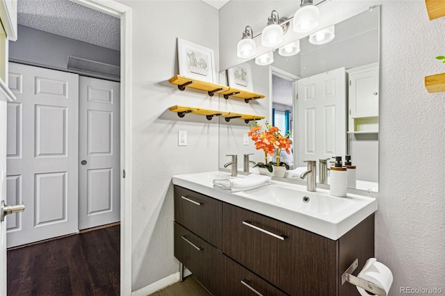 bathroom with wood-type flooring, vanity, and a textured ceiling